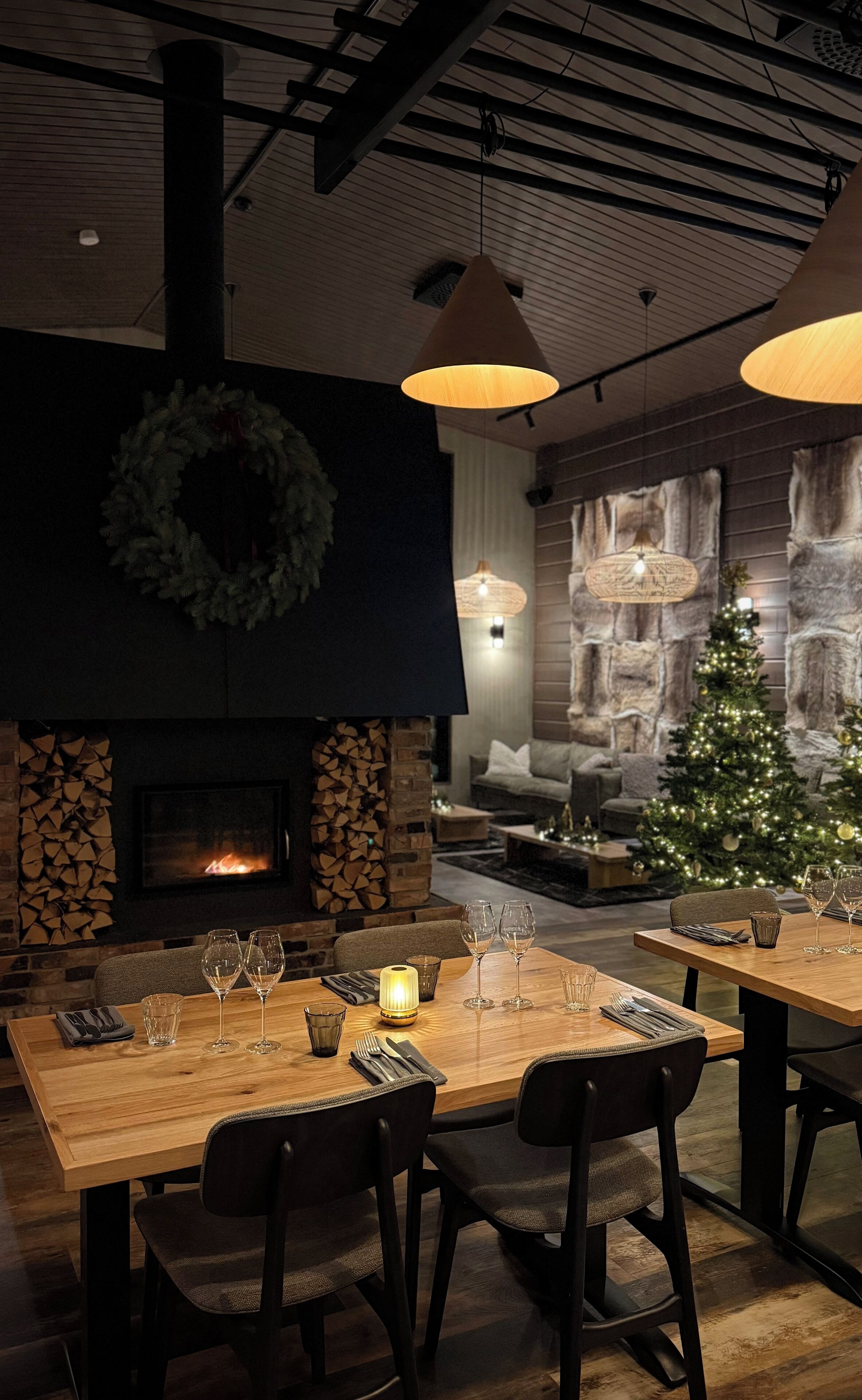 A cozy dining area with a fireplace, a Christmas tree, and a stone wall backdrop.