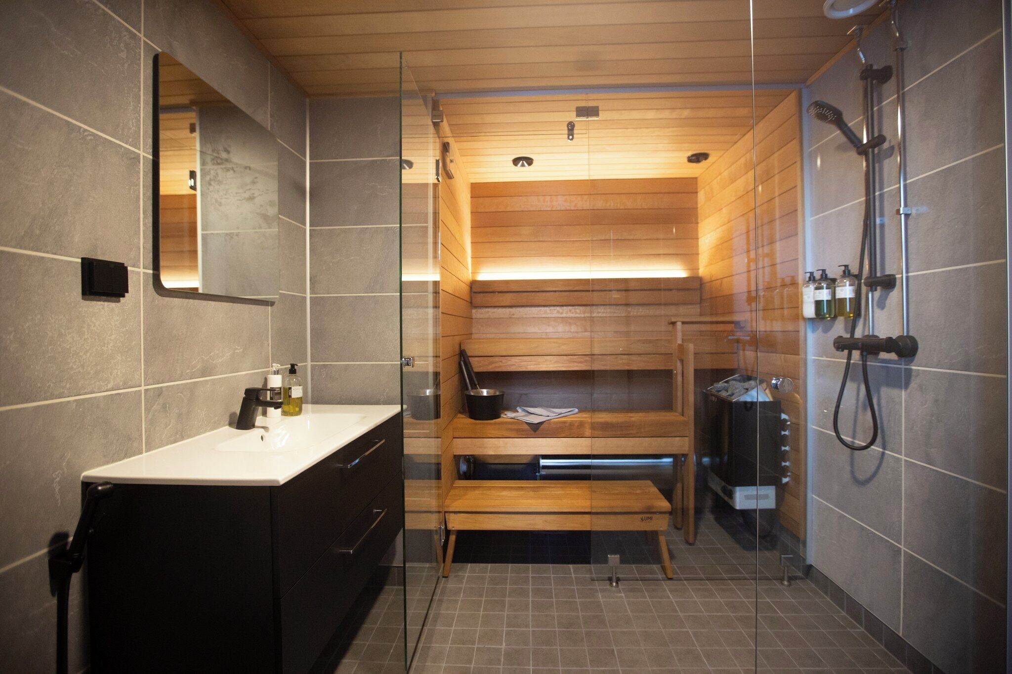 A modern bathroom with a wooden vanity, a glass shower enclosure, and a built-in bench.