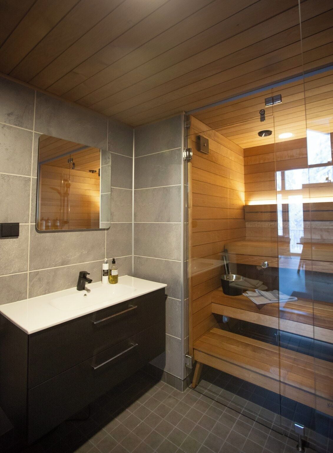 A modern bathroom with a large mirror, a white sink, and a glass-enclosed shower area.