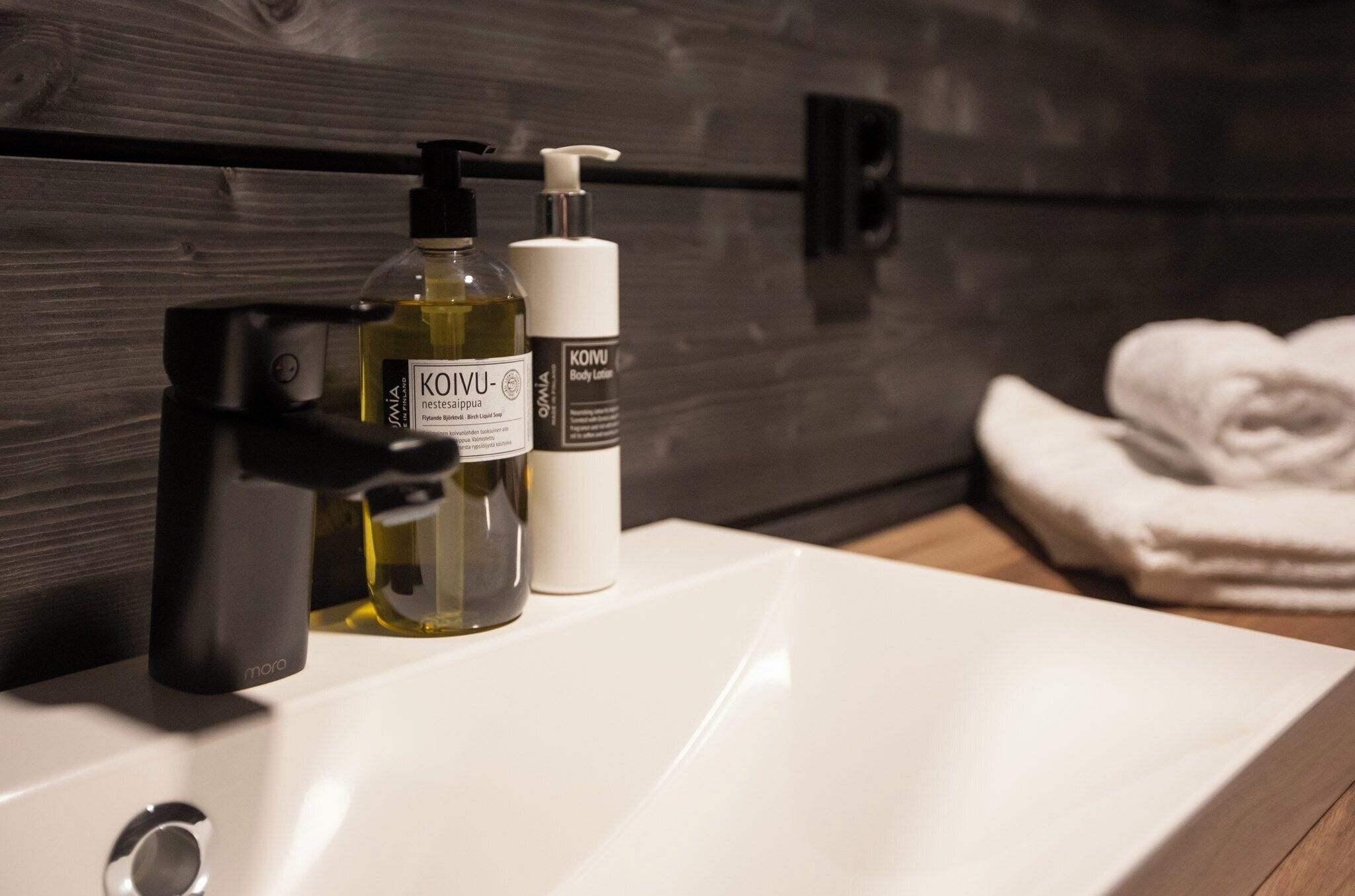 Un lavabo de salle de bain avec un flacon de lotion pour le corps KOUVU et un flacon-pompe de lotion pour le corps KOUMU.