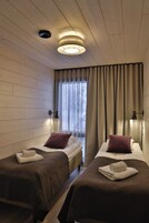 Una habitación de hotel con dos camas, paredes de madera, una ventana con cortinas y una lámpara en el techo.