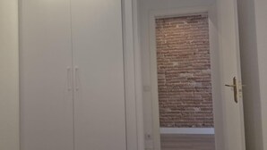 Une pièce avec une armoire blanche, un plancher en bois et un mur en briques.