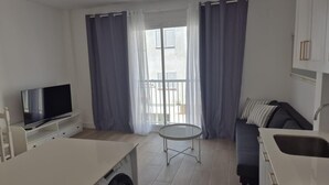 Un appartement moderne doté d’une télévision à écran plat, d’un lave-linge, d’une table à manger et d’un canapé.