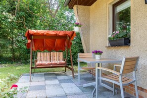 A patio with a swing chair, a table, and chairs.