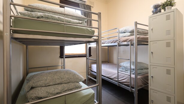 A dormitory room with bunk beds, a window, an air conditioning unit, and a set of lockers. - Emu Backpackers Perth - note - Valid Passport required for check in (Perth)