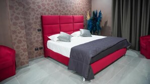 A modern bedroom with a red bed, white bedding, and a grey blanket. - HOTEL EL PAMAS (Mugnano di Napoli)