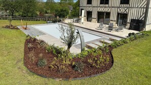 Une maison moderne dotée d’une grande terrasse, d’un espace salon extérieur et d’une piscine.