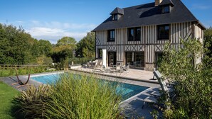 Une grande maison avec une piscine, du mobilier d’extérieur et un jardin.