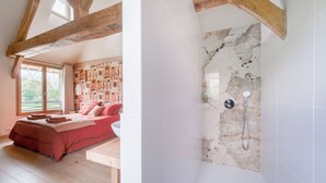 Une chambre avec un grand lit, un plafond en bois et une salle de bain avec douche.