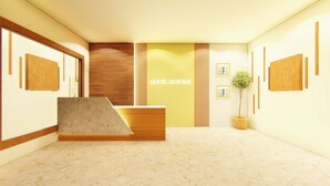 A reception area with a marble reception desk, a wooden accent wall, and a potted plant.