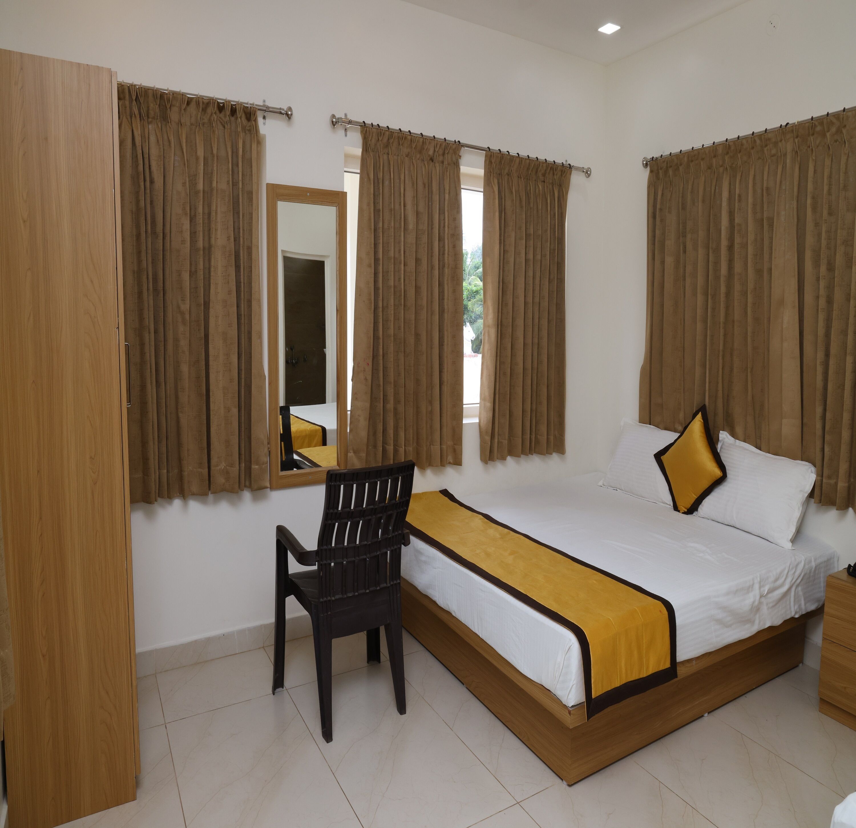 A bedroom with a bed, a chair, and a mirror.