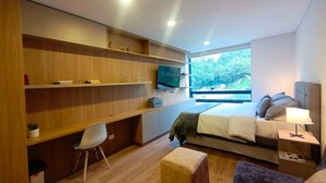 Un dormitorio moderno con cama, mesita de noche, televisor, estanterías de madera y un espacio de escritorio.