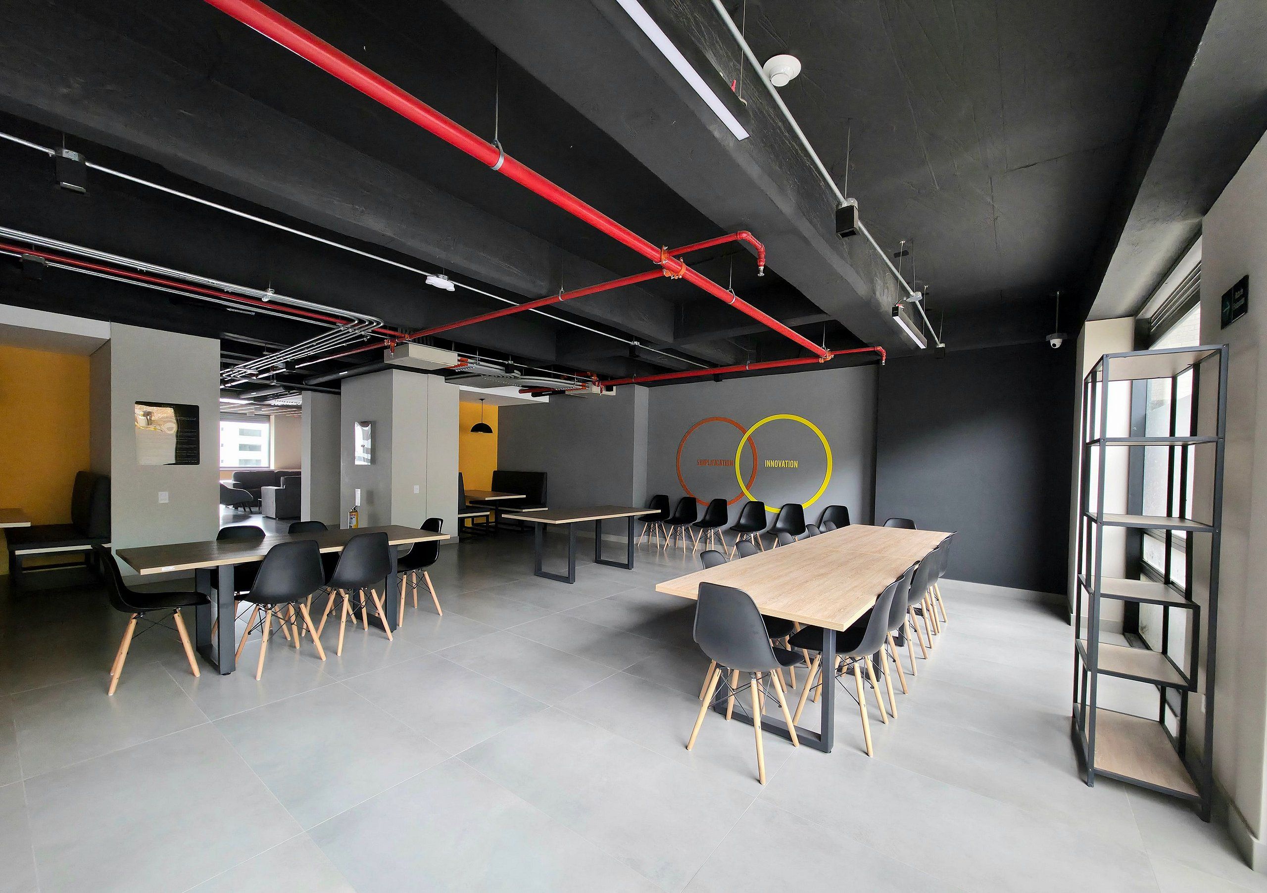 A modern conference room with long tables, black chairs, and a red ceiling.