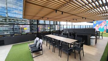 An outdoor dining area with a wooden ceiling, black chairs, and a table.