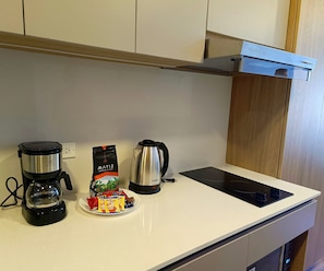 A kitchen with a coffee maker, a kettle, and a plate of instant coffee packets. - Loft 820 (Bogotá)