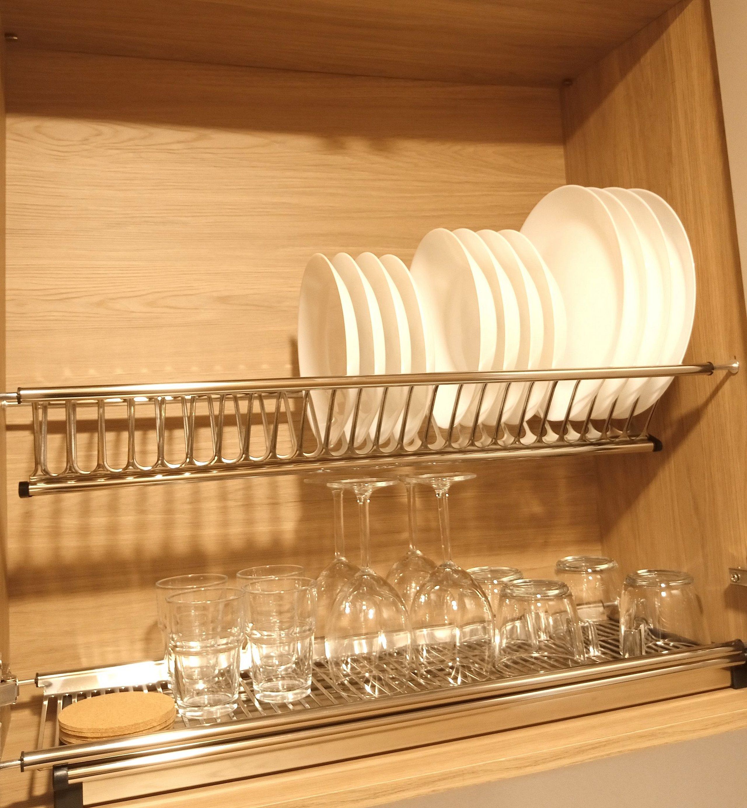 A kitchen cabinet with a dish rack holding plates and a wine glass rack with glasses.