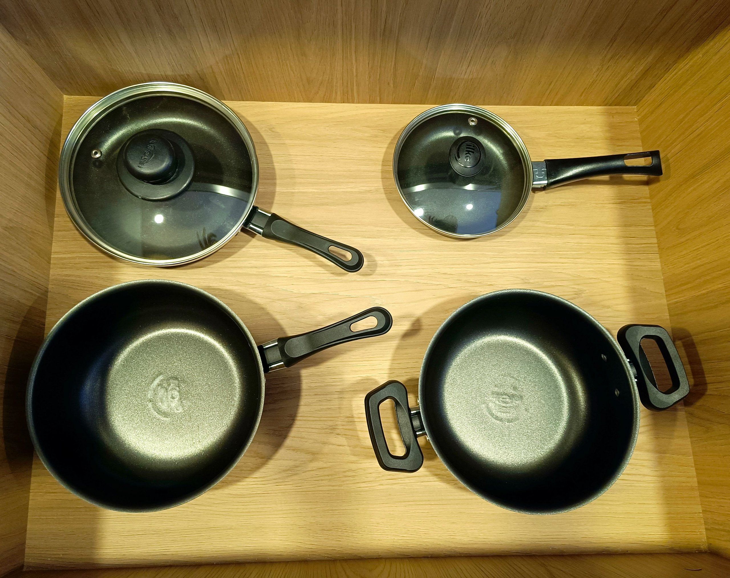Four cookware items in a wooden drawer.