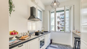 Cocina moderna con armarios blancos, encimera negra y un amplio ventanal.