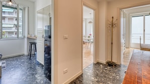 Una cocina moderna con armarios blancos, piso de mármol negro y una mesa de comedor de madera.
