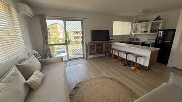 Eine moderne Wohnung mit Wohnzimmer, Küche und Balkon.