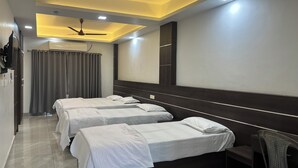 A hotel room with two beds, a ceiling fan, a TV, and a mirror. - Aroma Serviced Villa (Kanayannur)