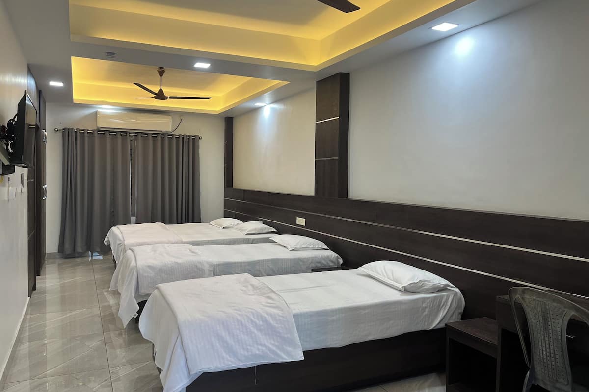 A hotel room with two beds, a ceiling fan, a TV, and a mirror.