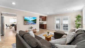 Ein modernes Wohnzimmer mit einem grauen Sofa, einem Couchtisch und einem an der Wand montierten Fernseher.