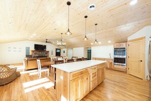 A spacious kitchen with wooden cabinets, a central island, and modern appliances. - Shady Rest Cabin #12, Brand-New 4-Bedroom Lakeside Cottage (Rhinelander)