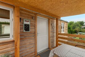 Una cabaña de madera con balcón, una puerta y una ventana.