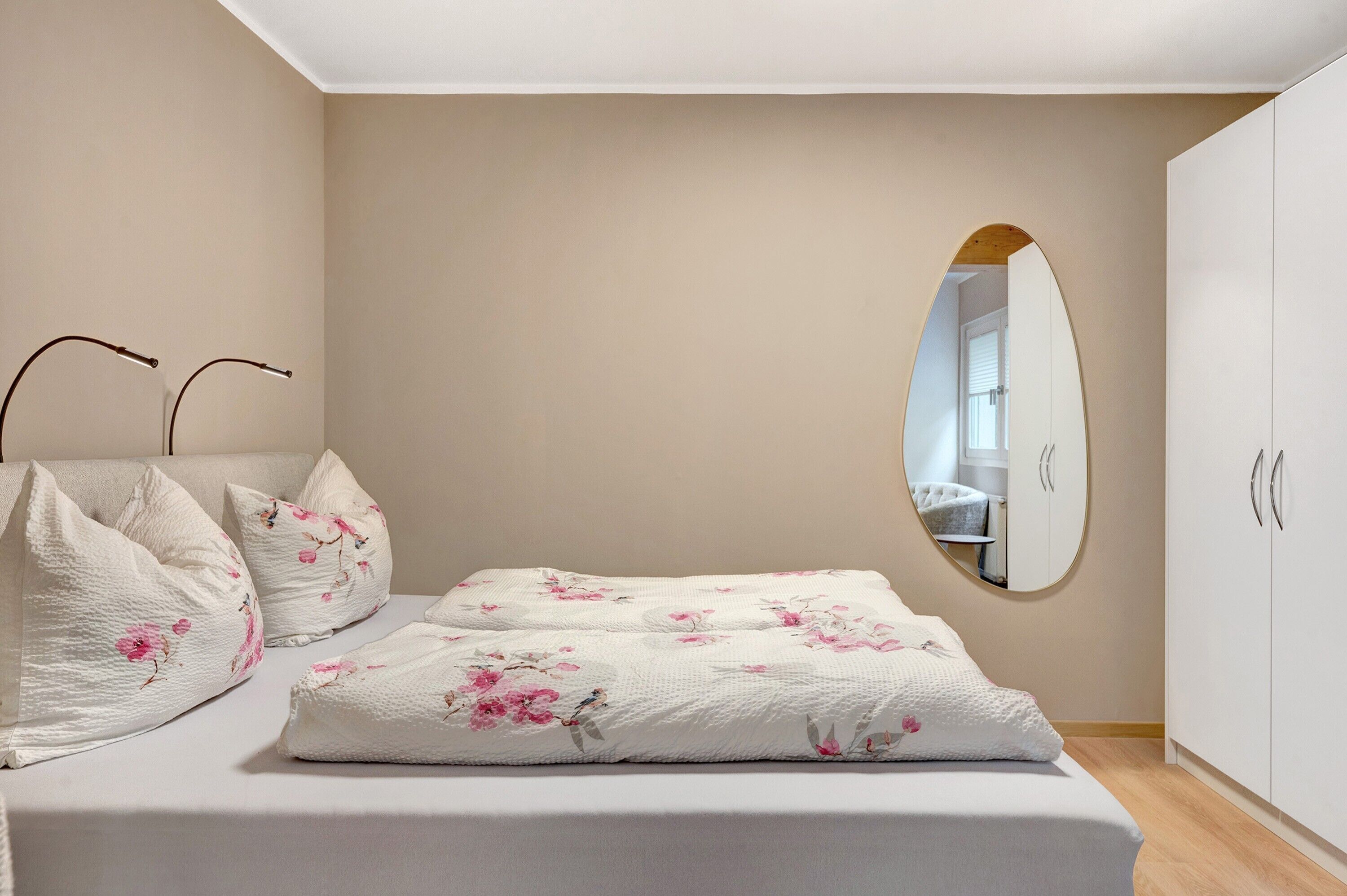 A bedroom with a bed, a mirror, and a wardrobe.