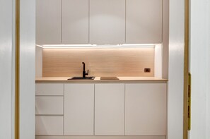 Una cocina moderna con un lavamanos empotrado, encimera de madera y armarios blancos.