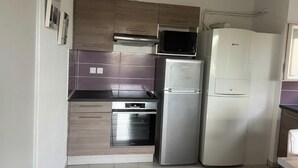 A compact kitchen with a built-in oven, a microwave, and a refrigerator. - T2 apartment with terrace, not overlooked, 3' from la Ramée leisure park (Tournefeuille)