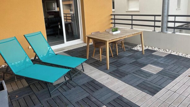 A patio with two blue lounge chairs, a wooden table, and a glass door leading to an interior space. - T2 apartment with terrace, not overlooked, 3' from la Ramée leisure park (Tournefeuille)