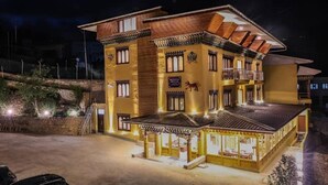 A multi-story building with a traditional architectural style, featuring balconies and a covered entrance area. - Paro Heritage Hotel (Paro)