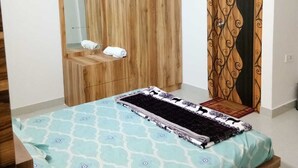Ein Schlafzimmer mit einem Bett, einem Holzschrank, einem Spiegel und einem gemusterten Vorhang.