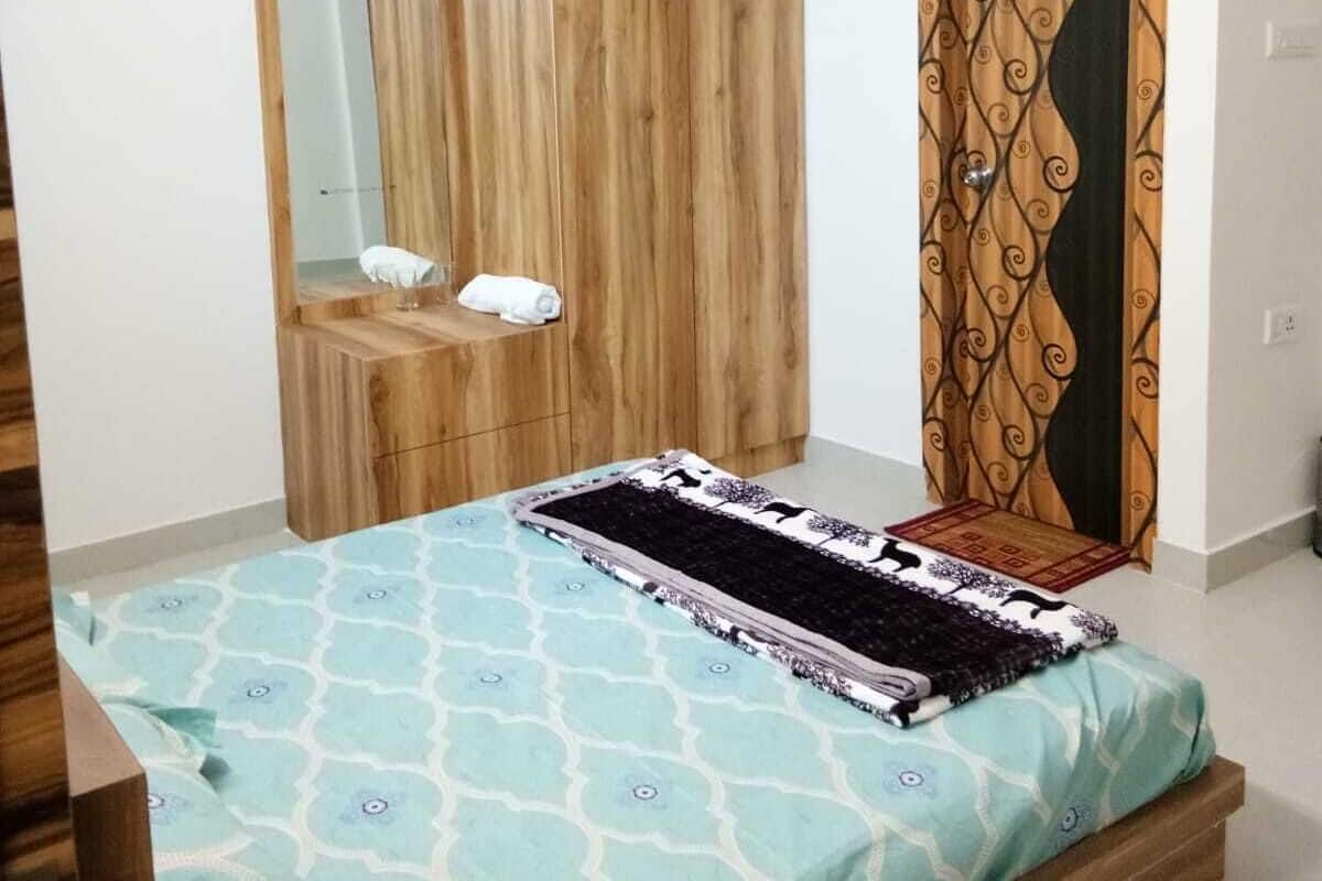 Un dormitorio con una cama, un armario de madera, un espejo y una cortina estampada.
