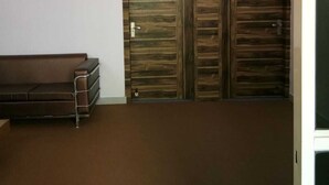 Ein Zimmer mit Deckenventilator, einem braunen Sofa und einem Holzschrank.