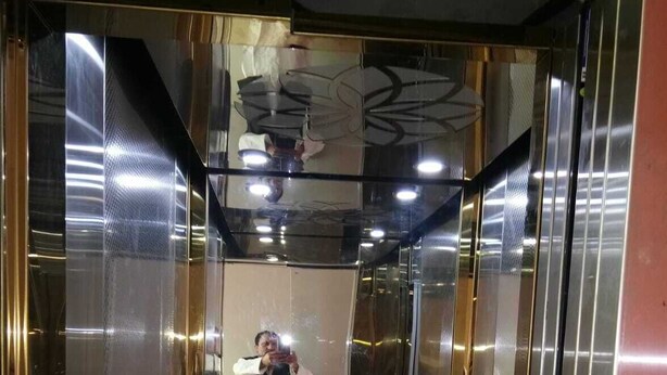 Ein Aufzug mit Metallwänden und einem spiegelnden Boden.
