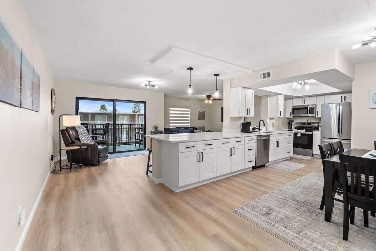 A modern kitchen with white cabinets, a central island, and stainless steel appliances.