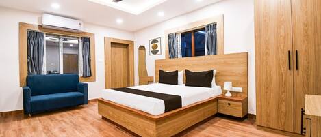 A modern bedroom with a wooden bed, a blue sofa, and a ceiling fan.
