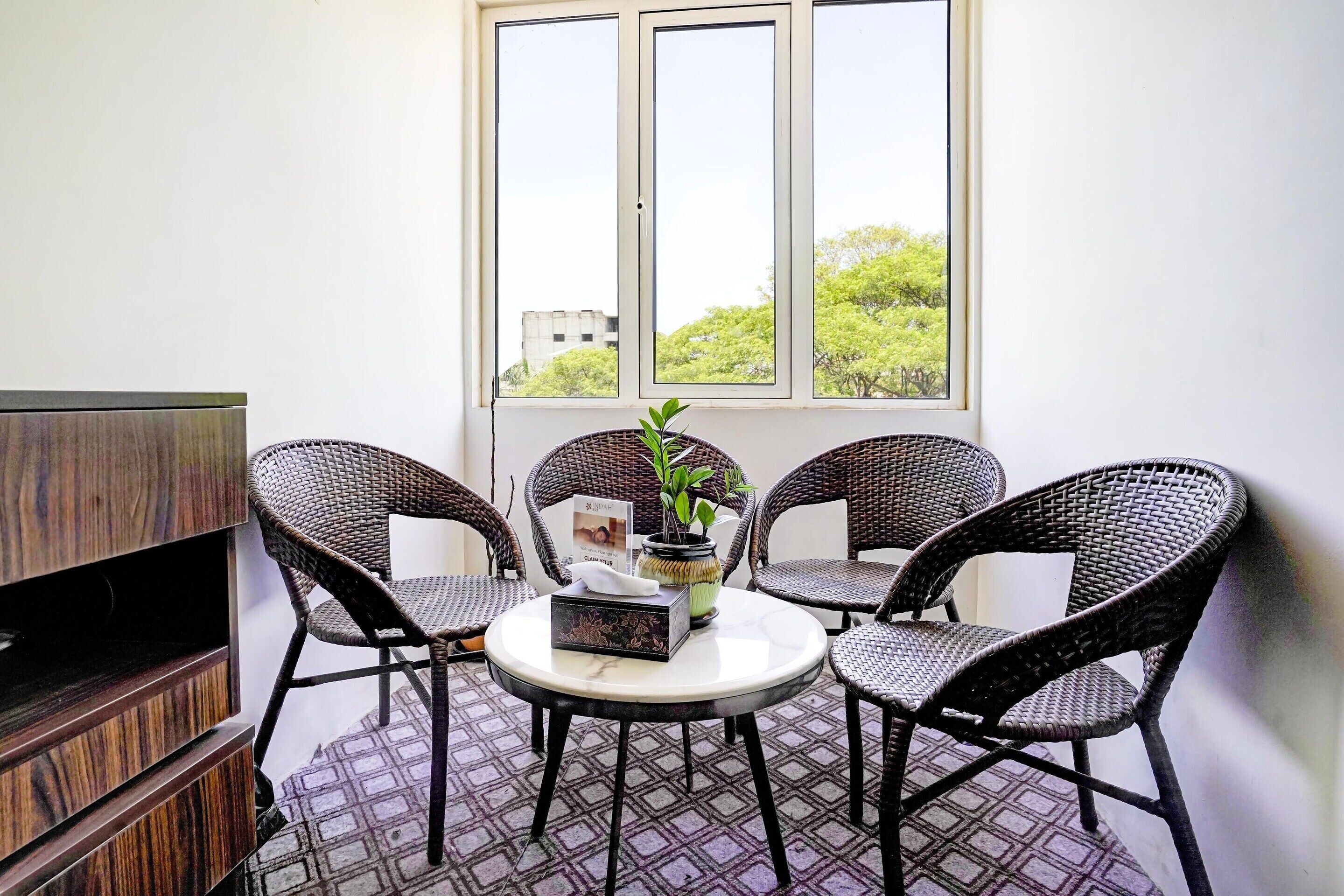 A small balcony with wicker chairs, a table, and a potted plant.