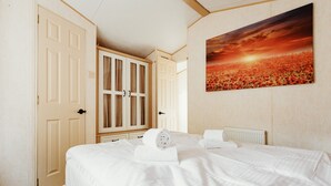 A hotel room with a bed, a painting of a sunset, and a wardrobe.