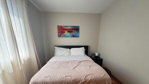Une chambre à coucher moderne avec un lit, une table de chevet et un tableau au mur.