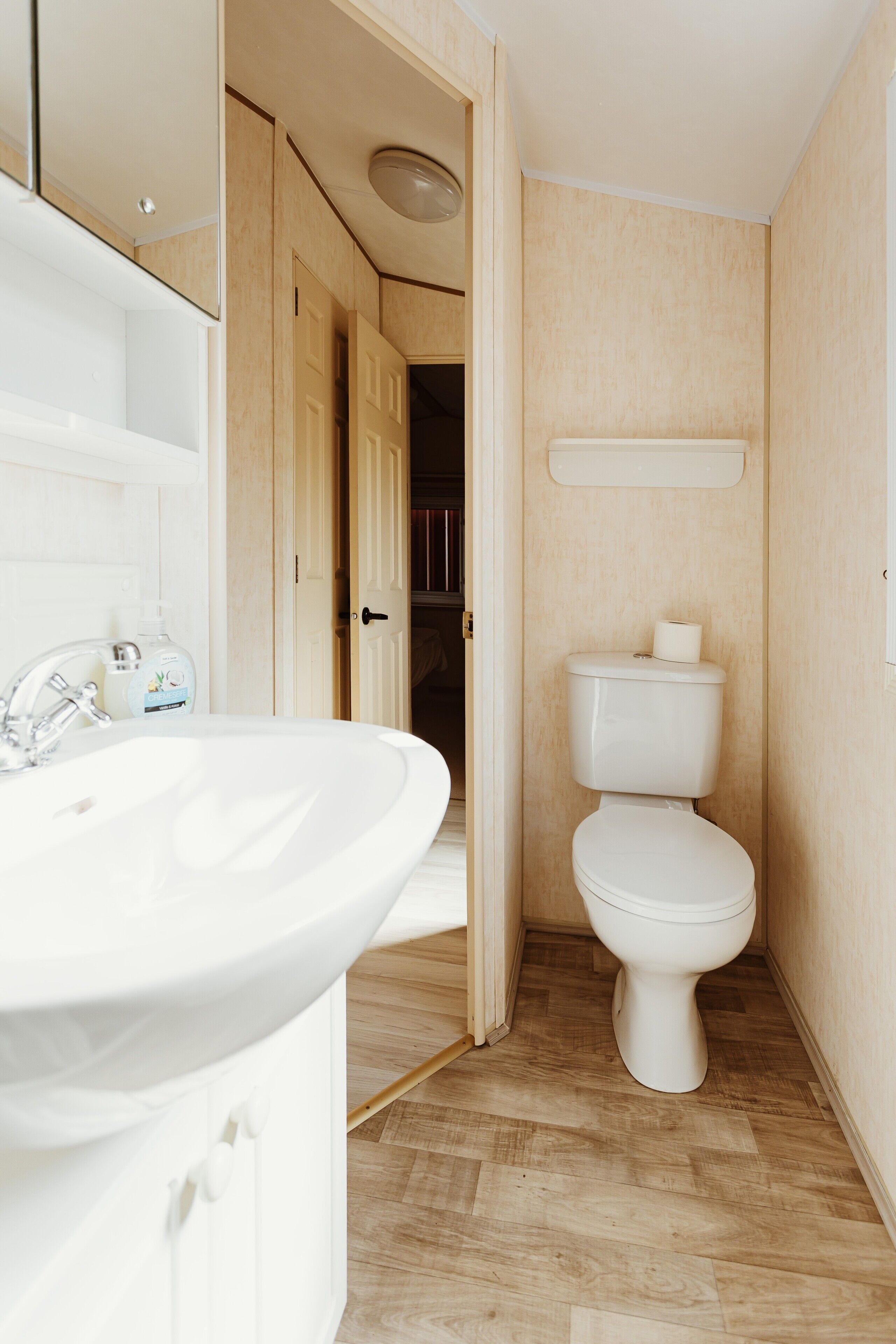 Ein Badezimmer mit Waschbecken, Toilette und Holzboden.