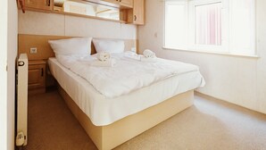 Een slaapkamer met een bed, houten kasten, een raam en een radiator.