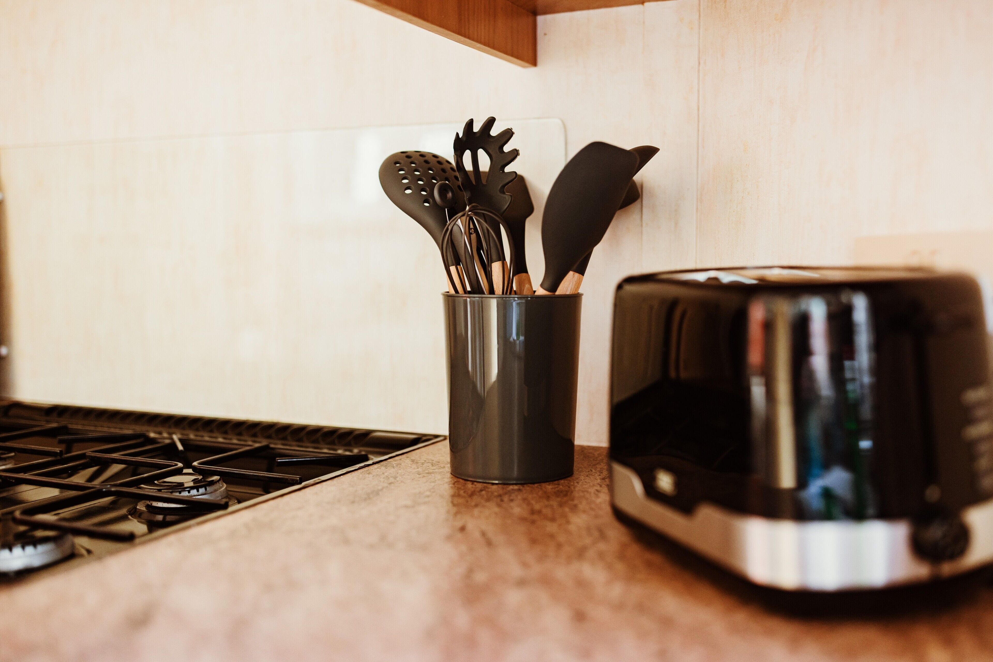 A kitchen with a toaster, a metal container with utensils, and a stove.