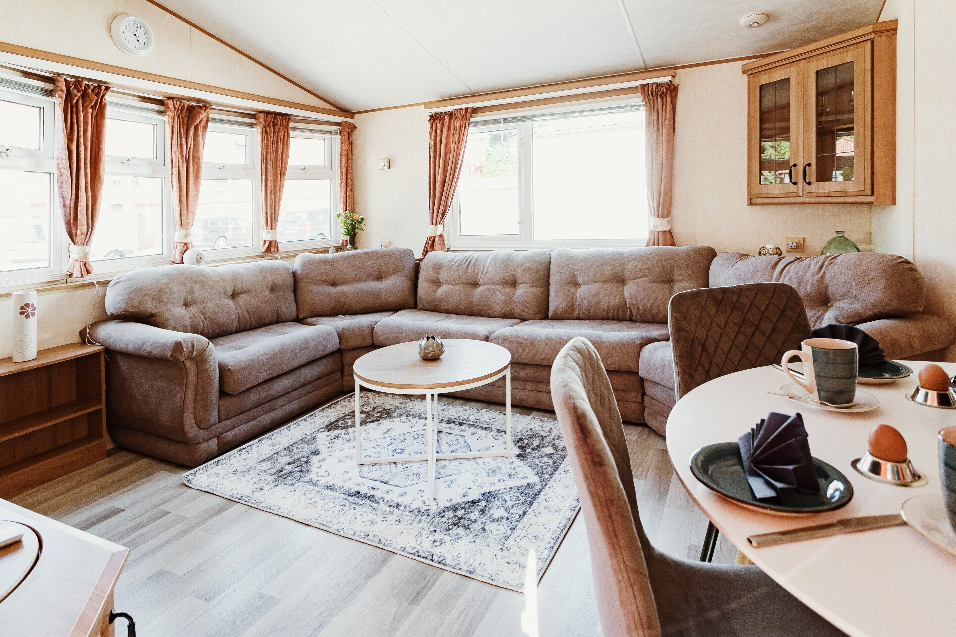 A cozy living area with a sectional sofa, a small round table, and a dining table set for two.
