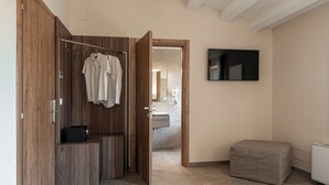 A modern bathroom with a wooden wardrobe, a hanging shower curtain, and a flat-screen TV mounted on the wall. - Manfredomus Farmhouse (Mussomeli)