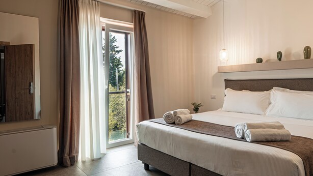 A hotel room with a large bed, a flat-screen TV, and a sliding glass door to the outside. - Manfredomus Farmhouse (Mussomeli)