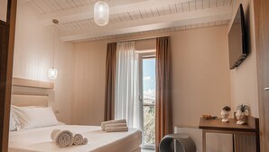 A hotel room with a bed, a round seating area, a table with decorative items, and a TV mounted on the wall. - Manfredomus Farmhouse (Mussomeli)